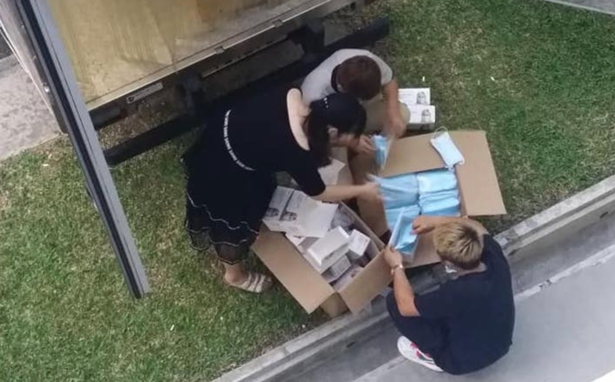 Three workers pack face masks into boxes in an image posted Monday to social media. Photo: Dee Umairah/Facebook
