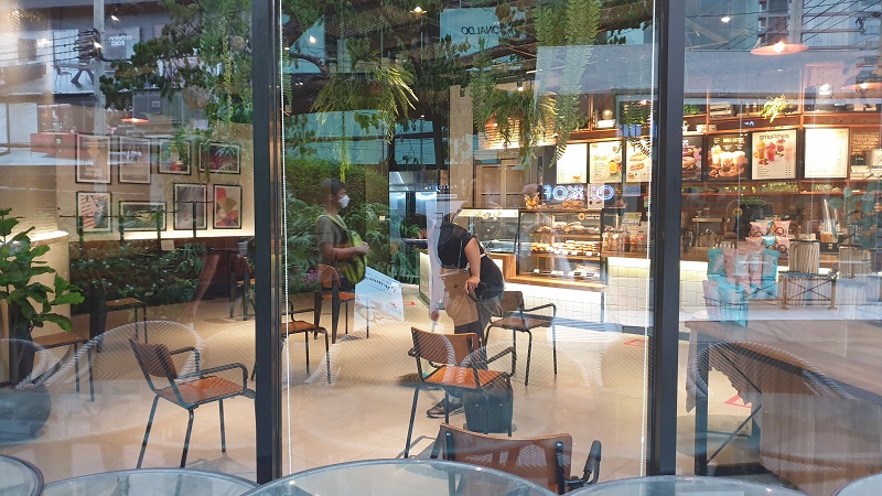 Passers-by reflected in the window of an Au Bon Pain outlet being cleaned in Bangkok’s Thonglor area on Tuesday afternoon.