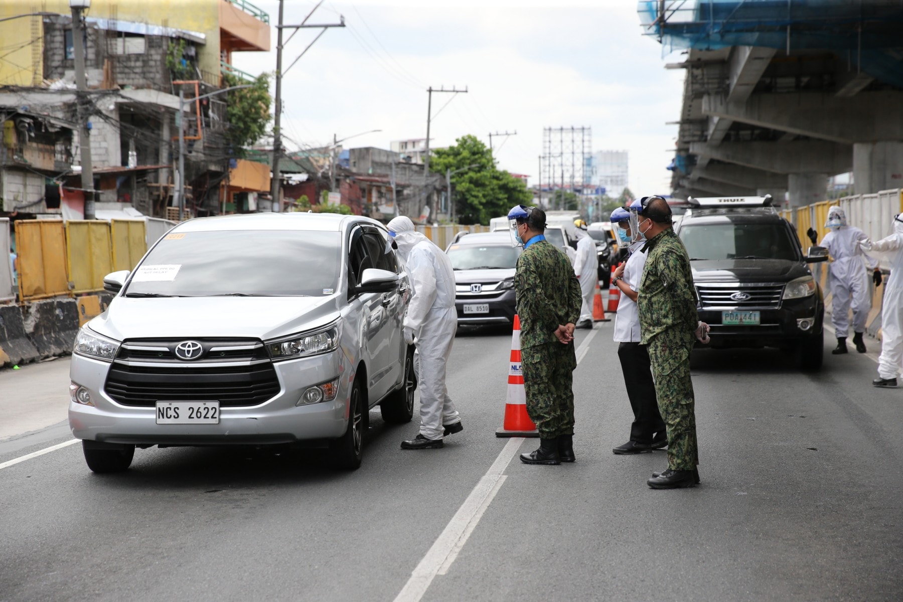 Cops and a medical worker inspect a car at a checkpoint. Photo: Philippine National Police/FB