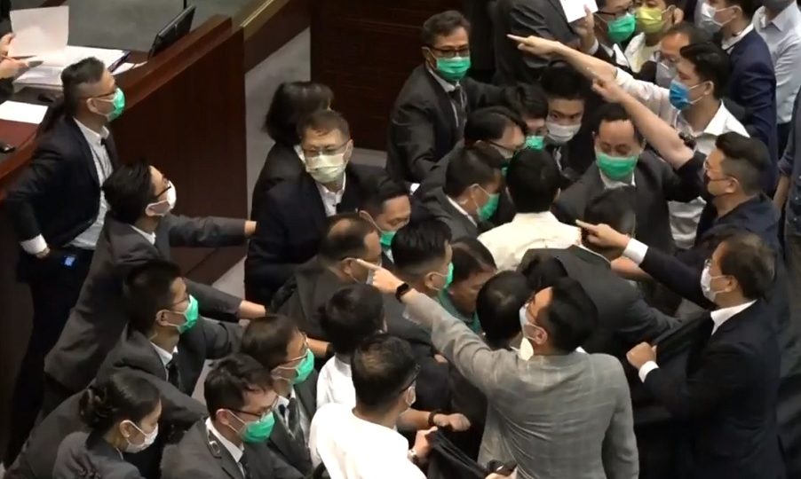 Pan-democratic lawmakers point at presiding member Chan Kin-po and accuse him of foul play as security guards hold them back from the podium. Screengrab: RTHK via Facebook