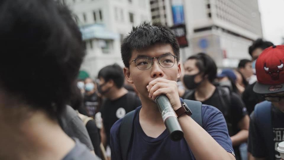 Joshua Wong speaks into a microphone during a march in Tsim Sha Tsui on July 7, 2019.