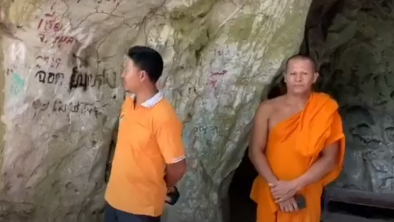 Volunteer guide Sathien Srikong and a monk from Wat Khao Pina stand inside Trang province’s Khao Pina Cave on Wednesday after it was defaced by vandals. Photo: Thai PBS / YouTube