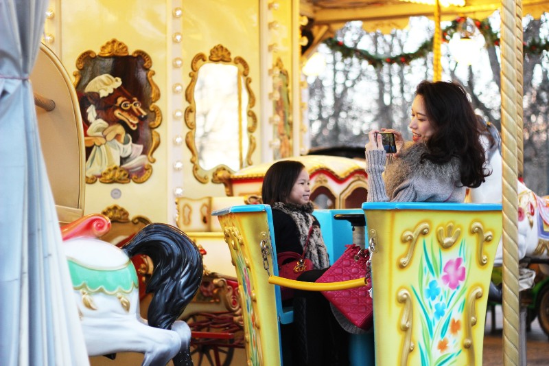 Mother and daughter taking photos on a merry-go-round. Photo: Loly Galina
