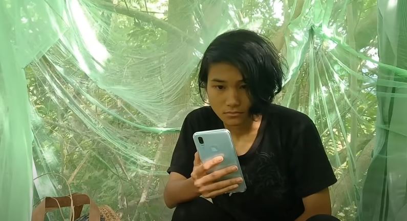 Veveonah Mosibin taking her online exams on the langsat tree under a mosquito net. Photo: Veveonah Mosibin / YouTube