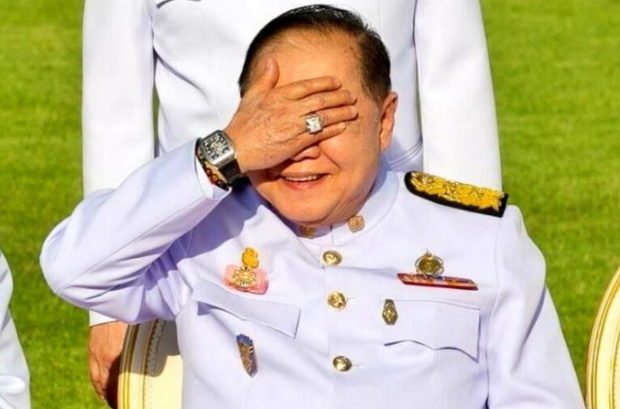 An image shows Prawit Wongsuwan in 2014 raised his hand to block the sunlight, tipping his bling wristwatch.
