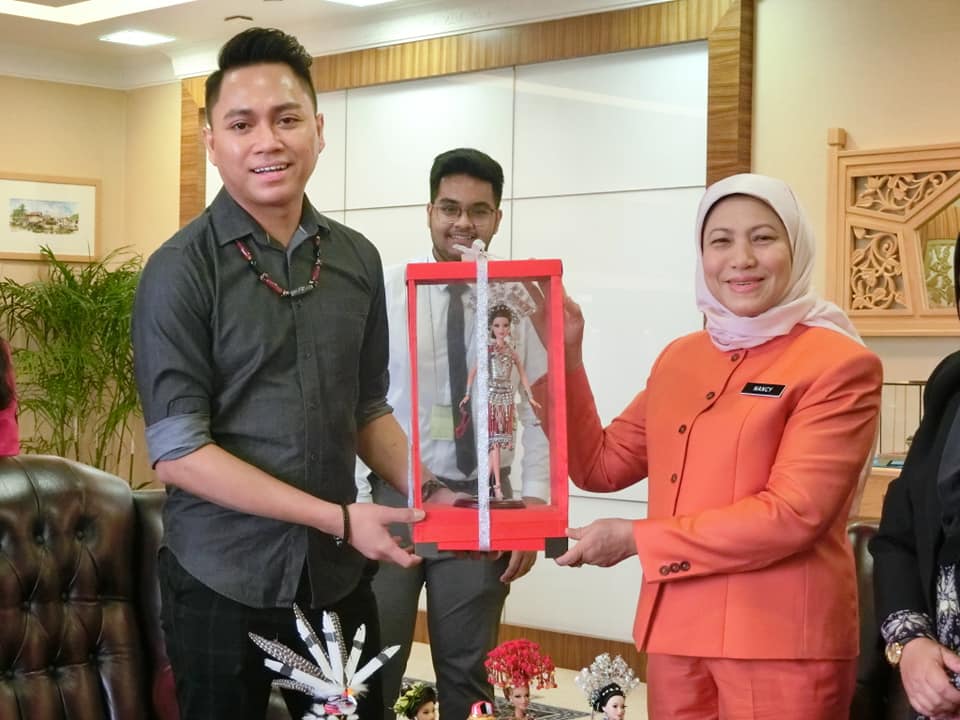 Wesley, at left, presents Tourism Minister Nancy Shukri with a Borneo Barbie doll. Photo: Nancy Shukri/Facebook
