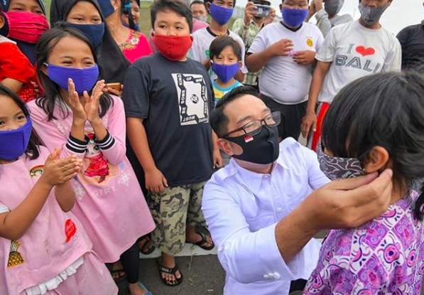 West Java Governor Ridwan Kamil giving away face masks to children in the province. Photo: Instagram/@ridwankamil