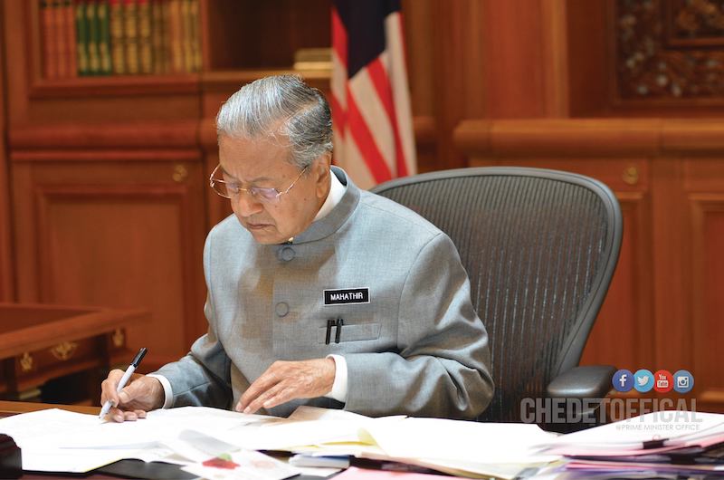 Mahathir pictured in his office, looking over some documents. Photo: Mahathir Mohamad /Facebook
