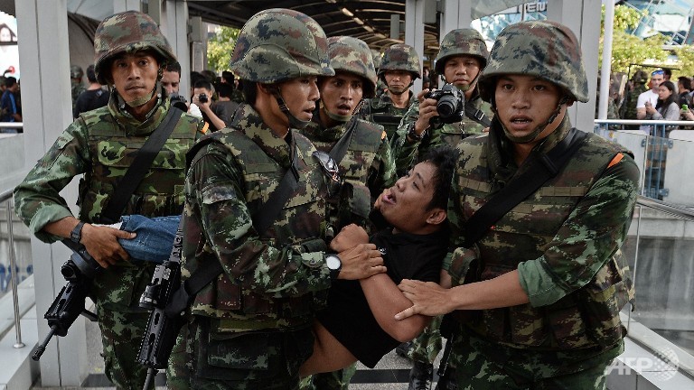 An anti-coup protester is taken away from the site of a gathering by Thai soldiers in Bangkok on May 24, 2014. Thailand’s military on Saturday disbanded the country’s Senate and placed all law-making responsibility in hands of the coup leader. Photo: AFP/Christophe Archambault

