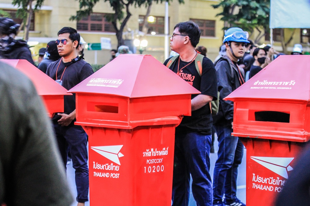 Protesters push makeshift mailboxes bearing the palace’s postal code Sunday from the Democracy Monument to the Grand Palace. The march culminated in thousands of protesters submitting letters addressed to King Vajiralongkorn. Photo: Coconuts 
