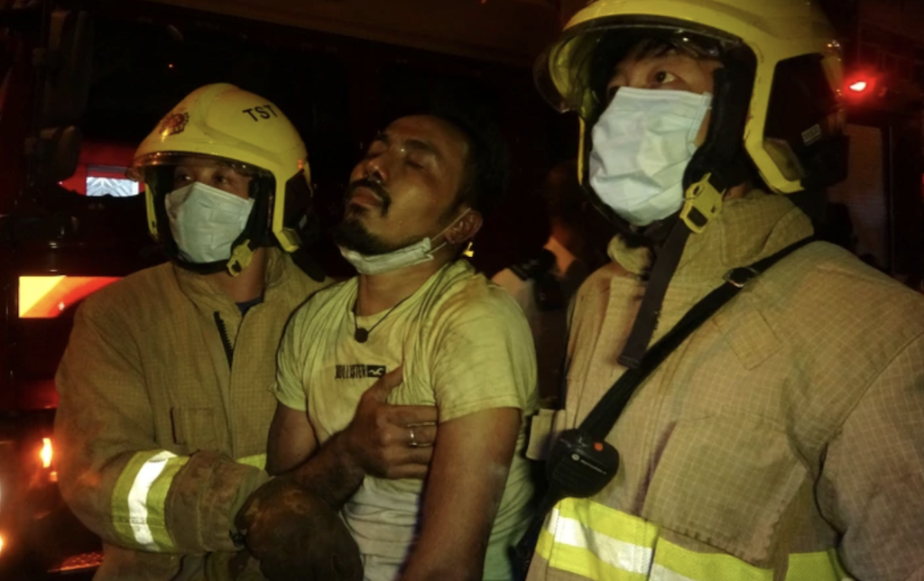 Firefighters escort a victim to safety after flames engulfed the Yau Ma Tei restaurant on Nov. 15, 2020. Photo via Apple Daily