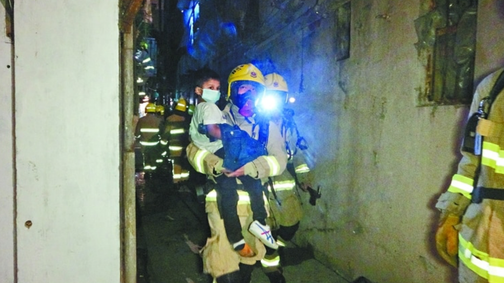 Firefighters rescue a boy from the restaurant, which had gone up in flames. Photo via Apple Daily