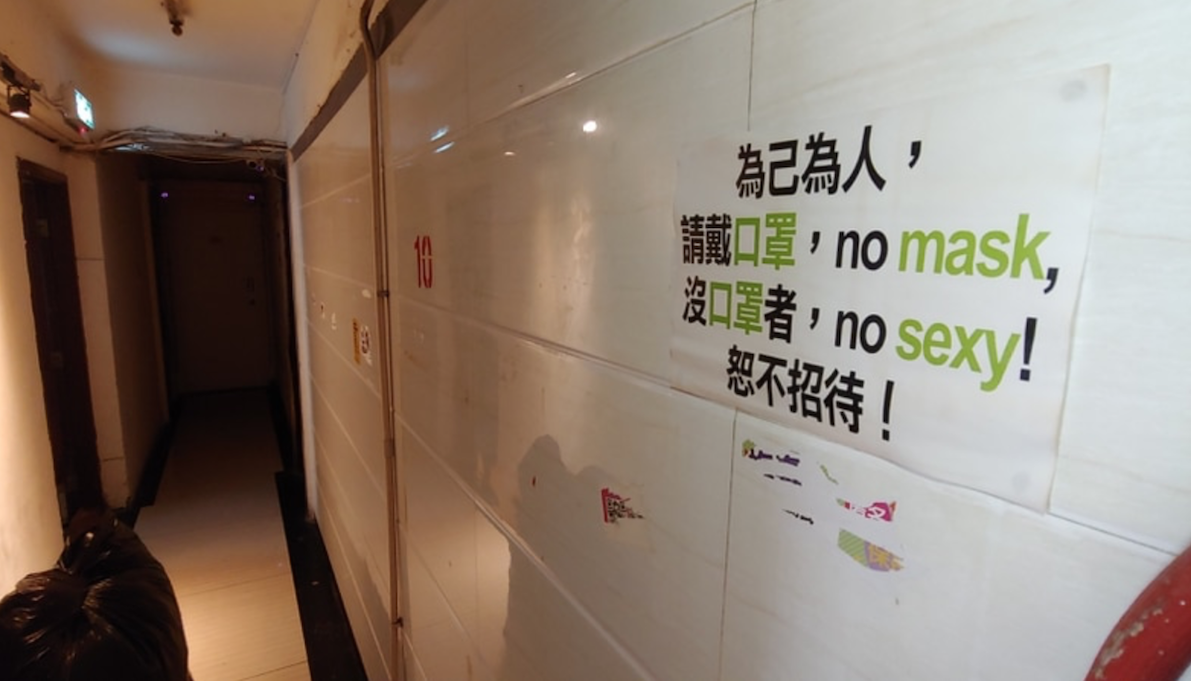 A sign outside one of the many brothels in the Mong Kok building reads “no mask, no sexy.” Photo via Apple Daily