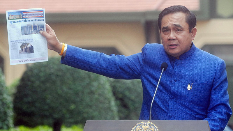 File photo of Gen. Prayuth Chan-o-cha holding a government newsletter in 2015. Photo: ThaiPublica 