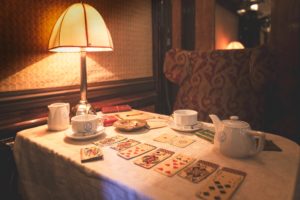 Playing cards are laid out on a table with tea service cups in a vintage Pullman carriage. Photo: Orient Express