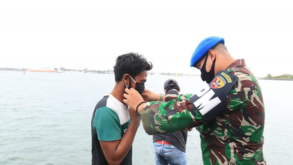 File photo of a military officer placing a mask on a local resident in January. Photo: Bali Provincial Government