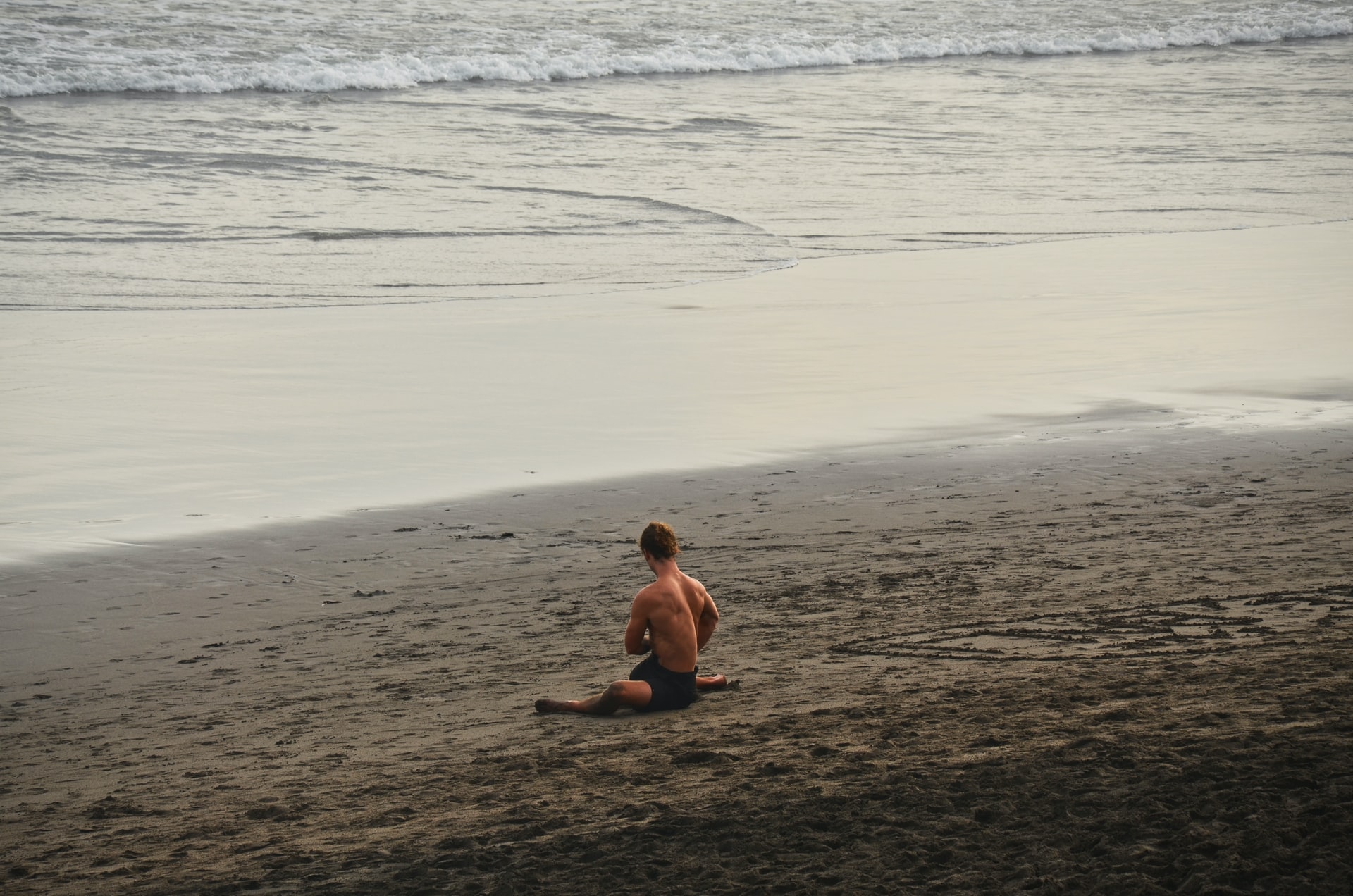 A man stretches on a beach in Bali. Photo: Unsplash