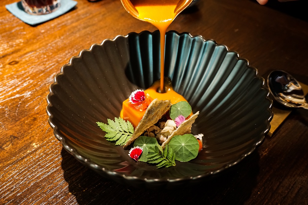 A colorful, eastern adaptation of ‘Kaeng Kradang’ with a thickened, bright orange-hued tomato consomme poured onto jellies made from sake-infused tomatoes and curry paste, deep-fried fish skins and boiled whelks. Photo: Coconuts