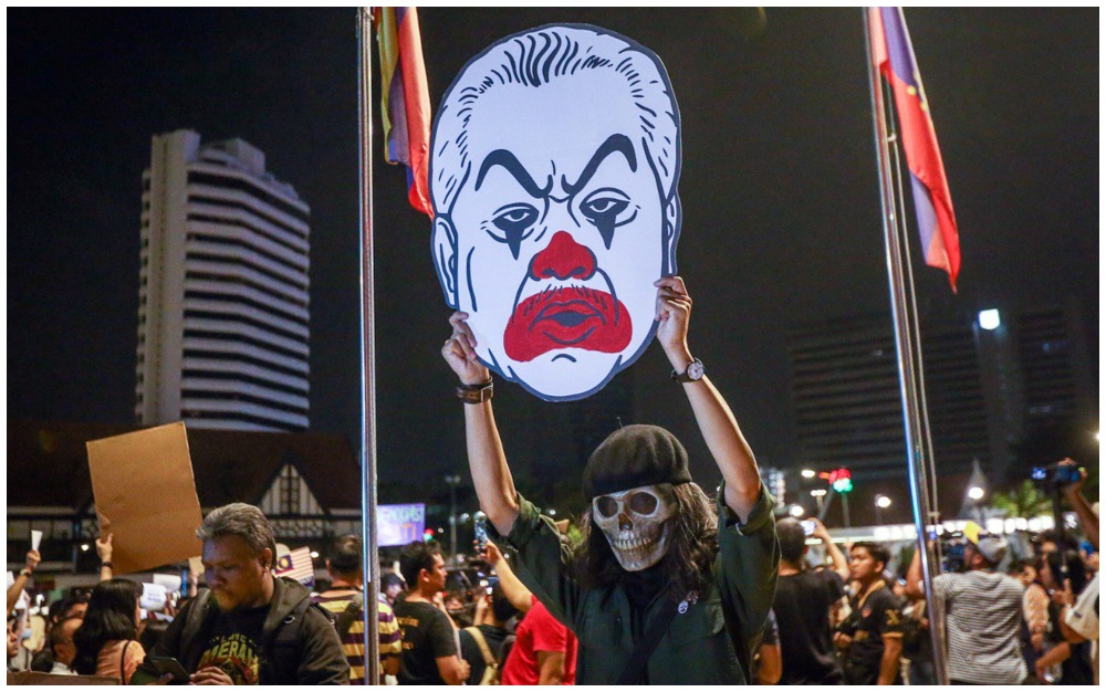 
Fahmi Reza holds his artworks depicting Prime Minister Muhyiddin Yassin in clown makeup. Photo: Fahmi Reza/Twitter
