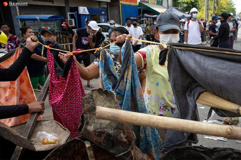 Women hang longyi garments to defend a protest site in Yangon.