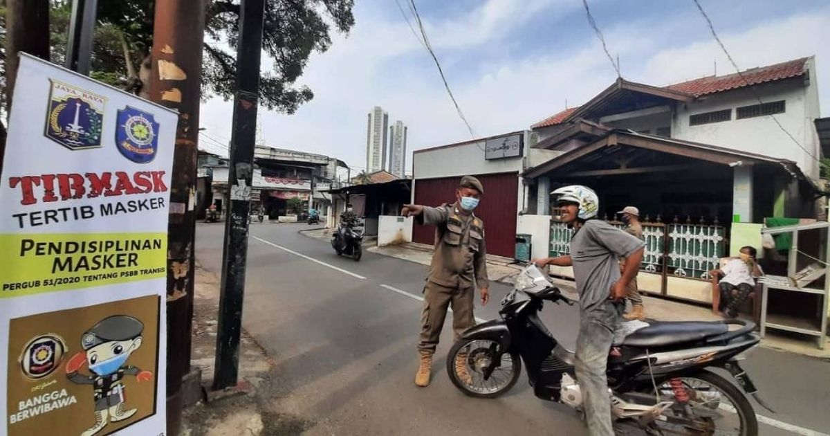 An officer from the Public Order Agency (Satpol PP) reminding a motorist to put on his face mask in West Jakarta. Photo: Twitter/@SatpolPP_DKI