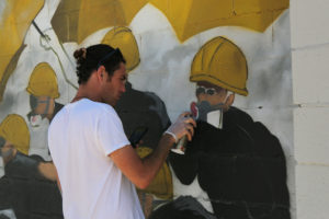 Mitchell is painting the gas masks of protesters in yellow helmets. Photo: Thirdblade Photography