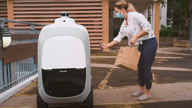 The Camello robot accepts a package delivery from a customer. Photo: Otsaw/YouTube
