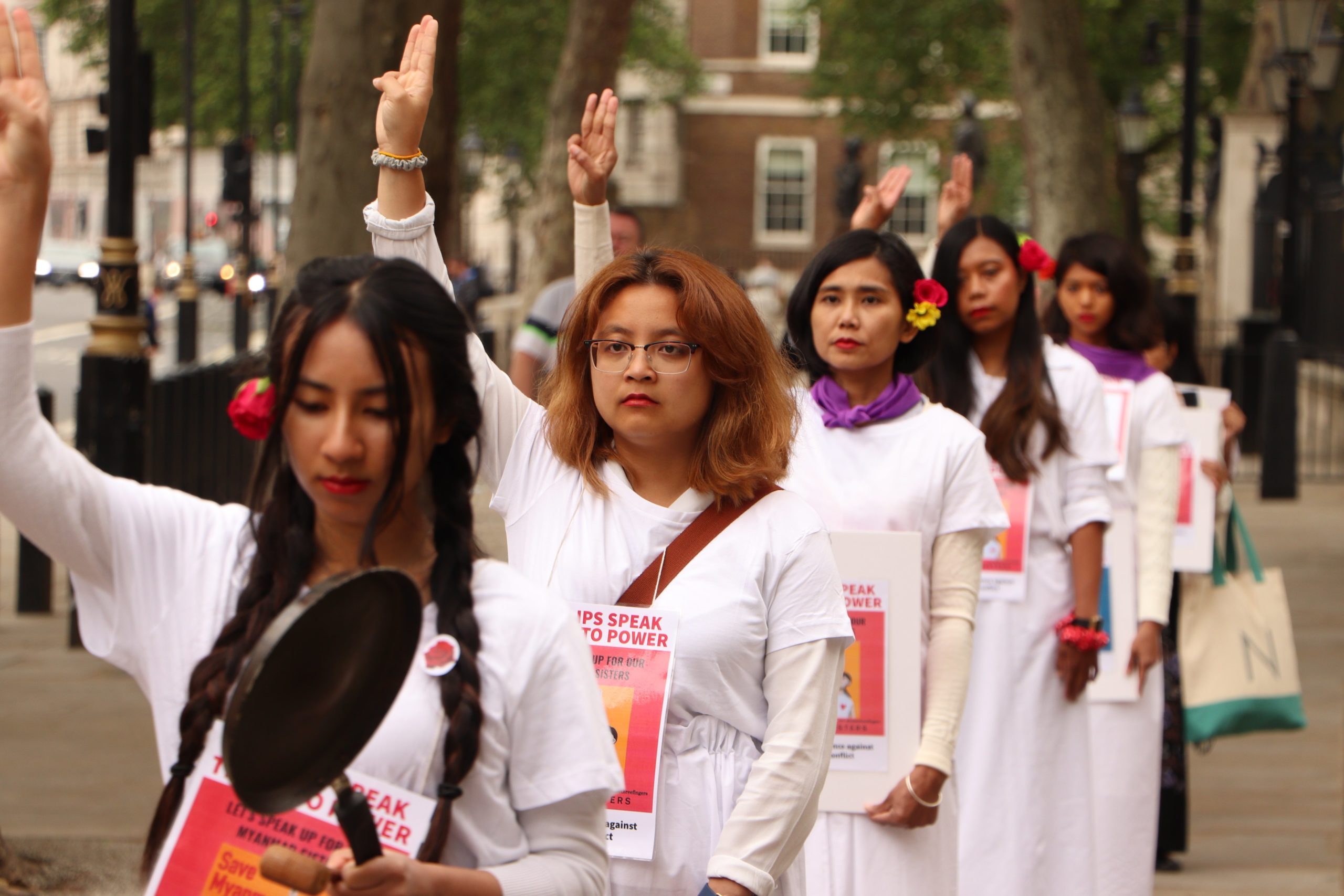 Women, wearing red lipstick and flowers, hold on three finger salute in London to protest against Myanmar military regime on June 19th, birthday of State Counselor Aung San Suu Kyi and International Day of the Elimination of Sexual Violence in Conflict. (Twitter)