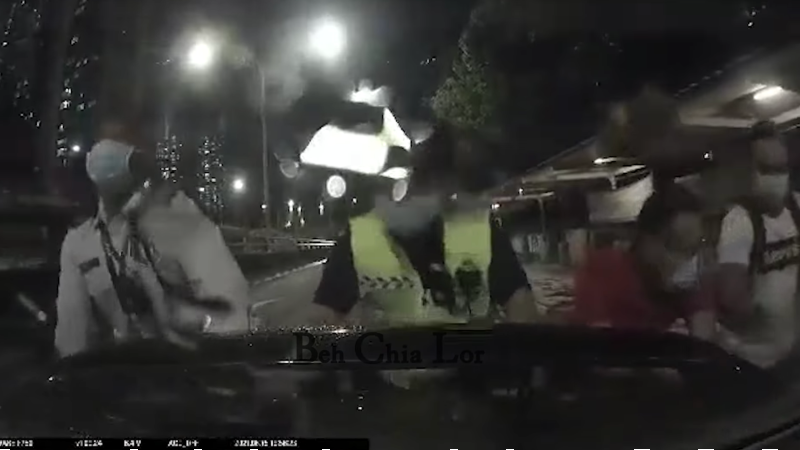 Screenshot of the video showing two traffic officers and two men pushing the car. Photo: Beh Chia Lor/Facebook
