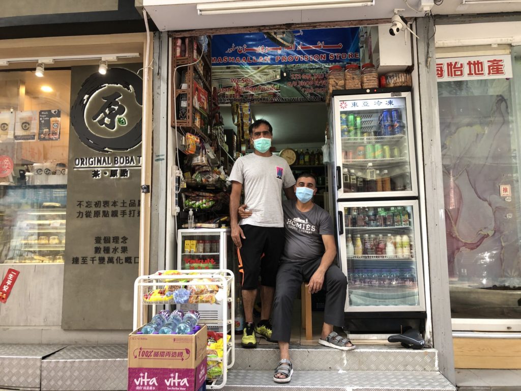 Wasal Khan (right) poses with a friend outside his shop. He pays around HK,000 (USalt=