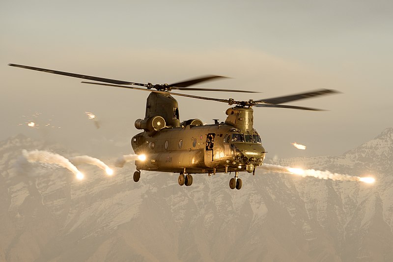 A Royal Air Force Chinook helicopter firing flares over Afghanistan in 2015. Photo by Cpl Lee Goddard (Open Government License v 1.0 via Wikimedia Commons)