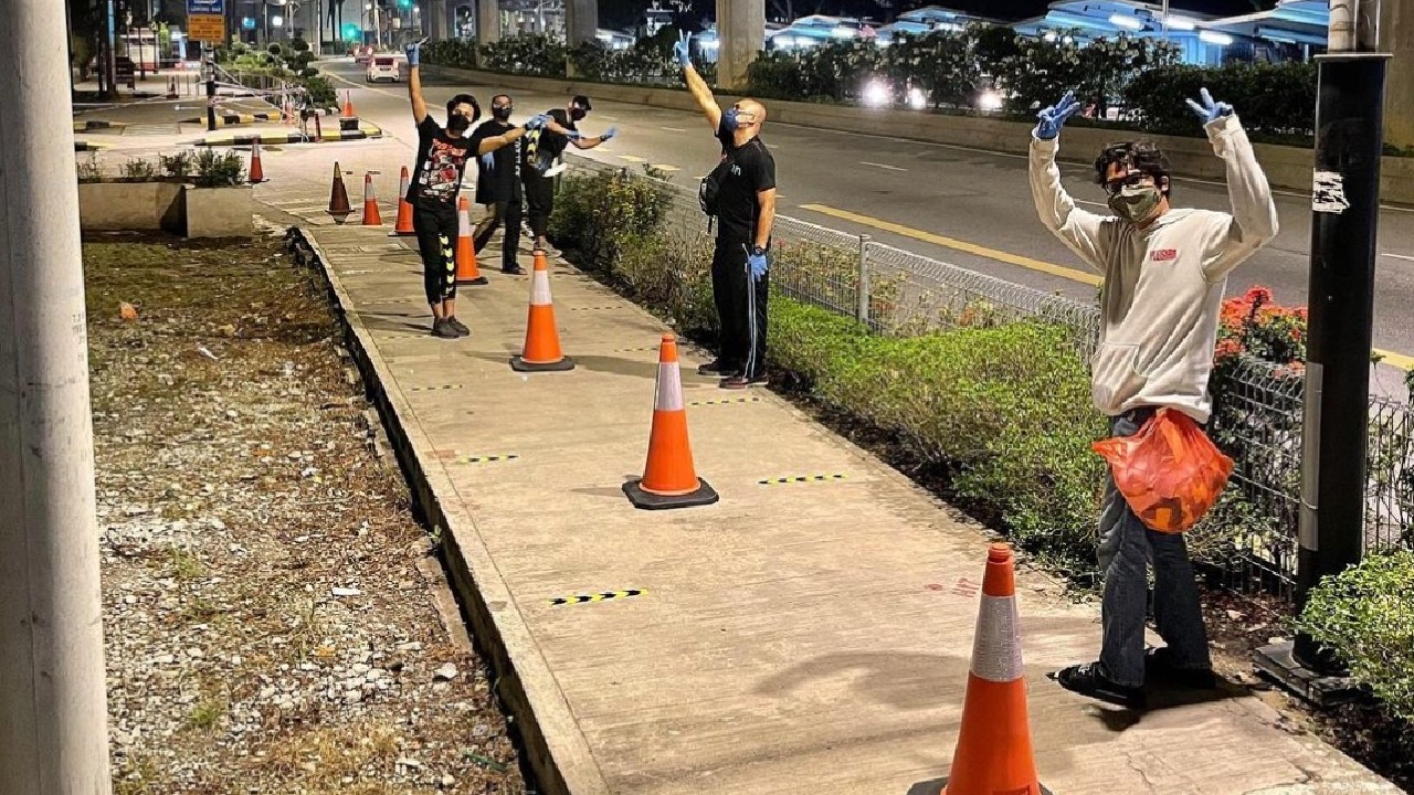 Volunteers help a Malaysian couple lay out traffic cones and paste tapes as social distancing markers outside Grand Season vaccination center on Aug. 11, 2021. Photo: sshakib.s/Instagram 