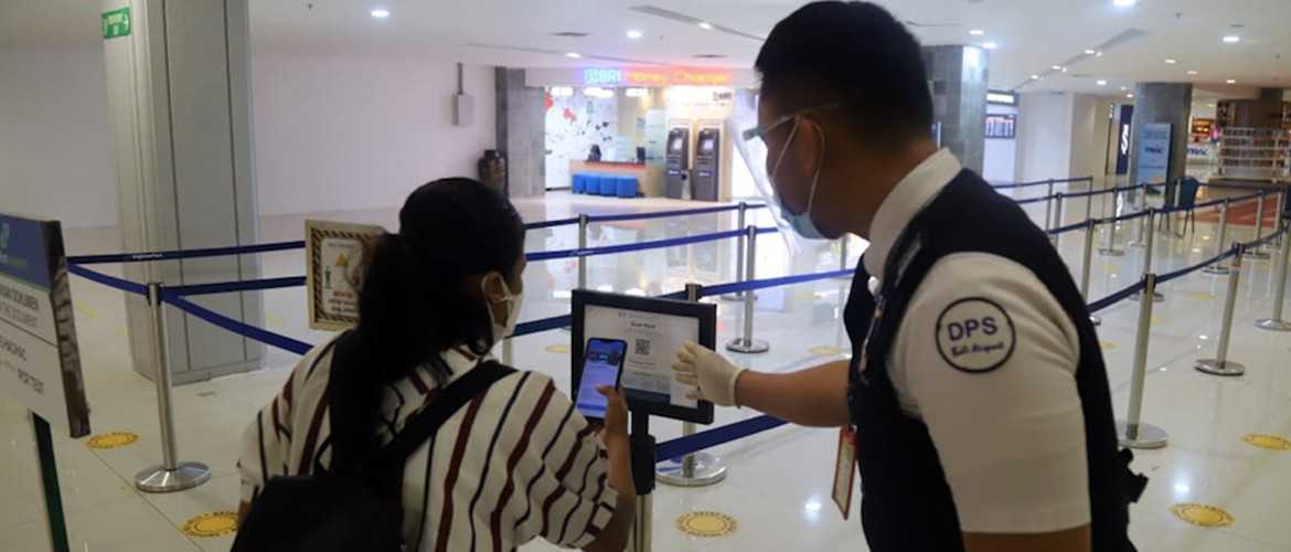 An airport officer showing a passenger how to use the PeduliLindungi app. Photo: Angkasa Pura I
