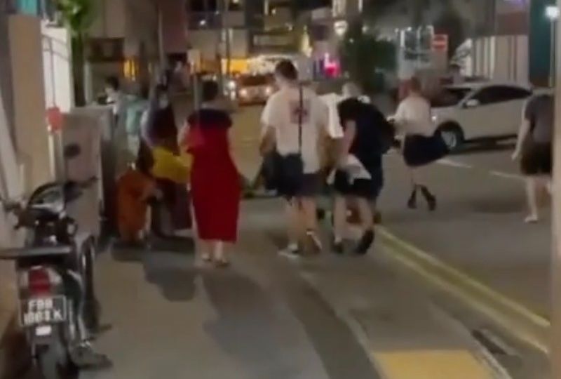 A yellow wet floor sign hits a girl, in orange, after it was smacked by a man wearing black. Photo: Wake Up Singapore/Instagram