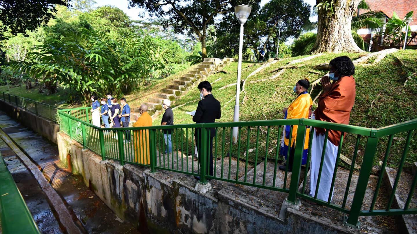 Religious leaders and neighborhood representatives pray Sunday at a canal in Upper Bukit Timah. Photo: Sim Ann/Facebook
