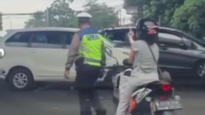 A motorcyclist in Jakarta giving the middle finger to a cop after he told her to put on a helmet. Photo: Video screengrab