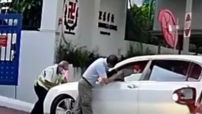 A white Bentley driver accelerates into a security guard blocking his path this morning at the Red Swastika School in Bedok. Photo: SG Road Vigilante/ Facebook
