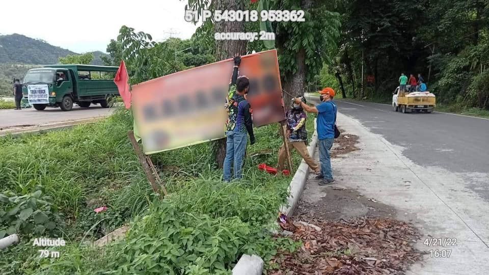 Personnel from the Department of Environment and Natural Resources take down posters tacked on trees. Image: DENR (Facebook)