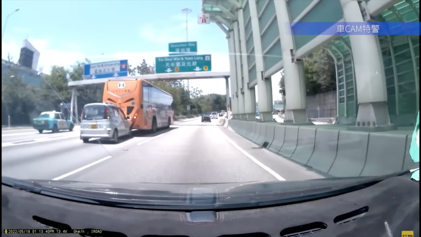 Screengrab of a YouTube video showing a school bus reversing on a busy road and pushing a car backward.