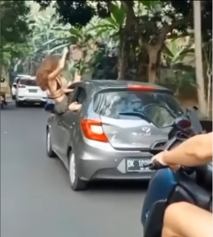 A video of a woman sat on a car’s window while the vehicle is speeding went viral on Sept. 19, 2022. The incident reportedly took place in Karangasem a day earlier. Photo: Screengrab.