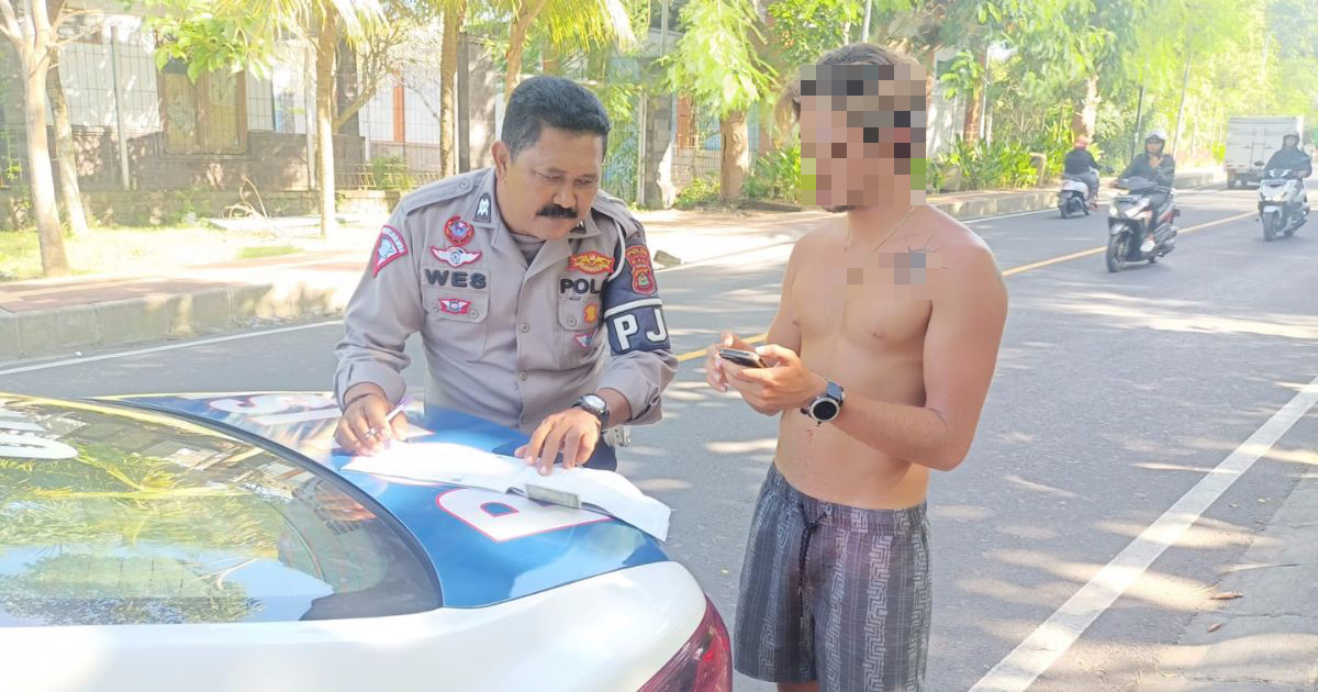 Police ticketing a shirtless motorcyclist for not wearing a helmet. Photo: Handout by Bali Police
