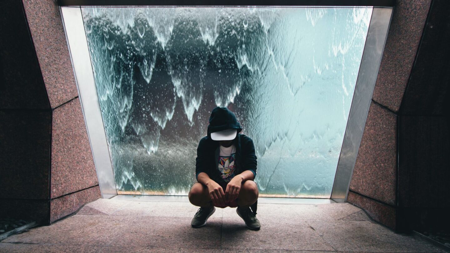 A despondent man squatting in front of the Fountain of Wealth in Suntec City. Photo: Unsplash
